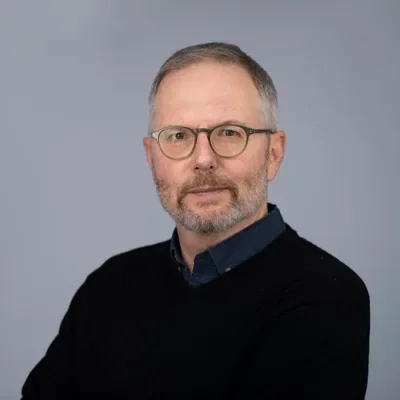 Professional headshot of man with glasses and beard