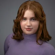 Professional headshot of woman with reddish-brown hair in purple sweater