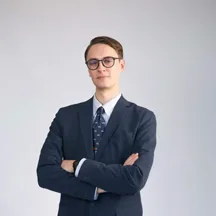 Professional headshot of young man with glasses in navy suit