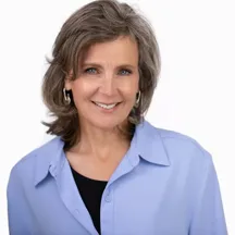 Professional headshot of woman with shoulder-length brown hair in light blue shirt