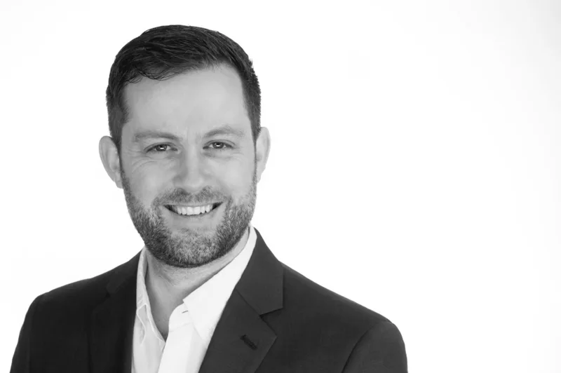 Professional headshot of man with beard in suit