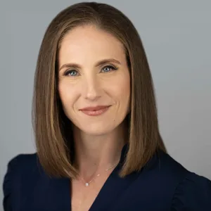 Professional headshot of a woman with shoulder-length brown hair wearing a navy blue top